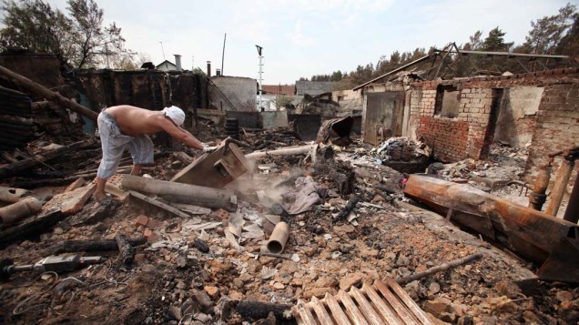 Homem recolhe detritos de sua casa queimada em Voronezh, na Rússia