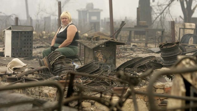 Mulher senta sobre os restos de sua casa queimada em Mokhovoye, a 130 km de Moscou