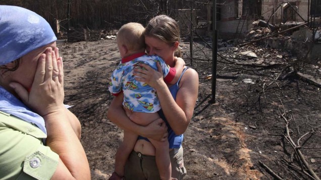 Mulheres choram ao encontrar suas casas queimadas em Voronezh, na Rússia