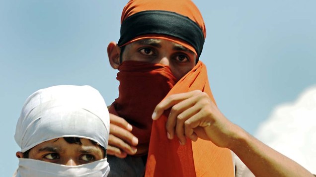 Manifestantes cobrem seus rostos durante protesto em Srinagar, na Índia, em 18 de agosto