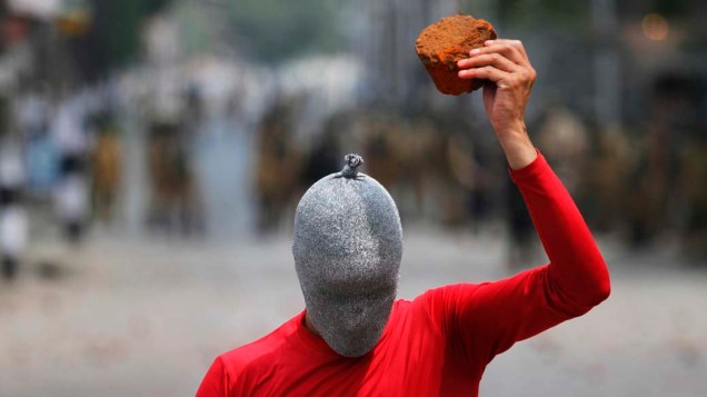 Durante protesto em 13 de agosto em Srinagar, na Índia, manifestante atira pedras em militares