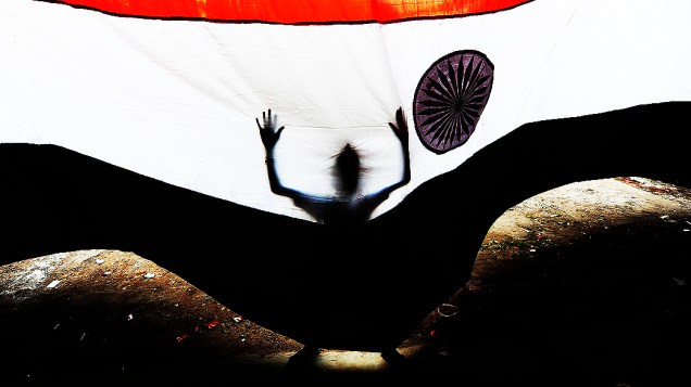 Menino atrás da bandeira da Índia, para a cerimônia que celebra o Dia da Independêndia