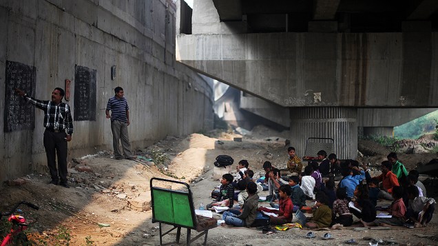 Alunos participam de aula gratuita para crianças pobres, debaixo de um viaduto em Nova Déli, Índia