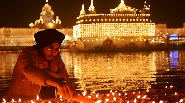 Devoto indiano sikh acende lâmpadas no Templo Dourado de Amritsar