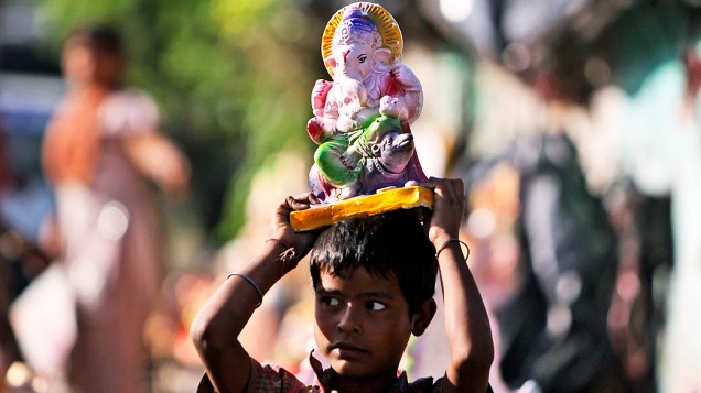 Menino carrega estátua do deus Ganesh, durante celebração de Ganesh Chaturthi Festival em Jammu, na Índia