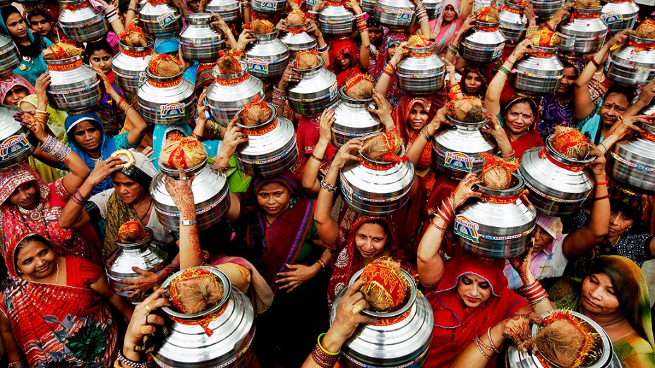 Mulheres indianas carregam potes de água e cocos em um ritual hindu em Nova Délhi, na Índia