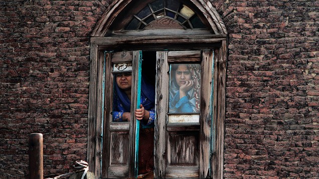 Mulheres muçulmanas da Caxemira olham para fora de uma janela em Srinagar, na Índia, durante protesto contra o governo