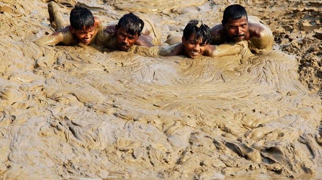 Homens se jogam na lama do rio Ganga, na cidade de Allahabad, na Índia