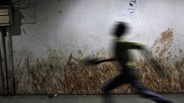 Menino passa por uma parede manchada com cuspo de tabaco ao longo de uma rua em Nova Delhi