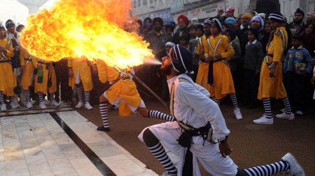Jovem cospe fogo durante uma procissão no Santuário Sikh, Índia