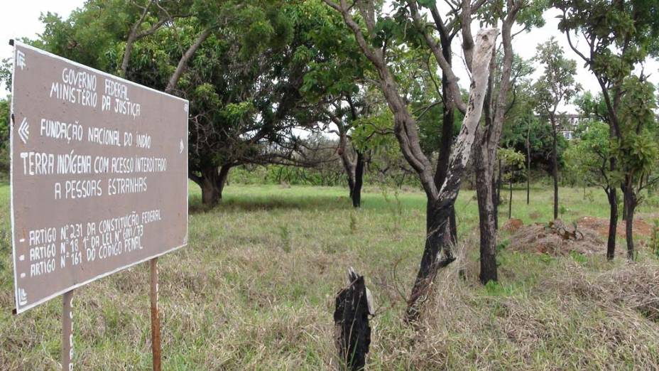 Placa feita pelos moradores proibe entrada de pessoas estranhas. Ao fundo, prédio em construção