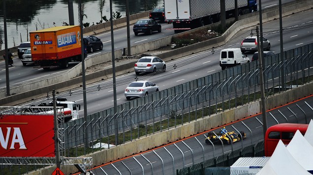 Carros e caminhões na Marginal Tietê passam junto a pista do sambódromo do Anhembi durante treino livre da fórmula Indy
