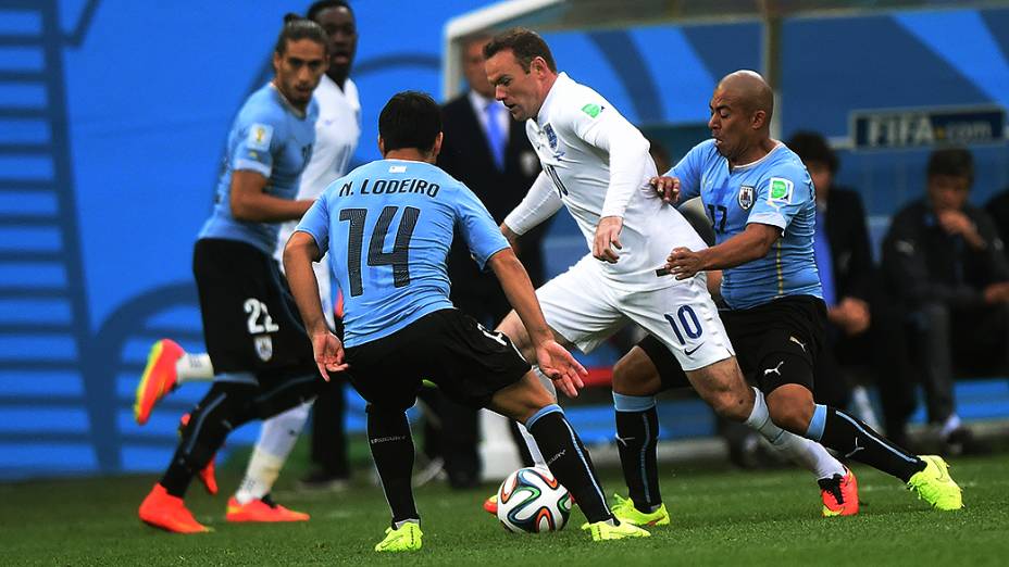 O inglês Wayne Rooney é marcado por dois jogadores do Uruguai no Itaquerão, em São Paulo