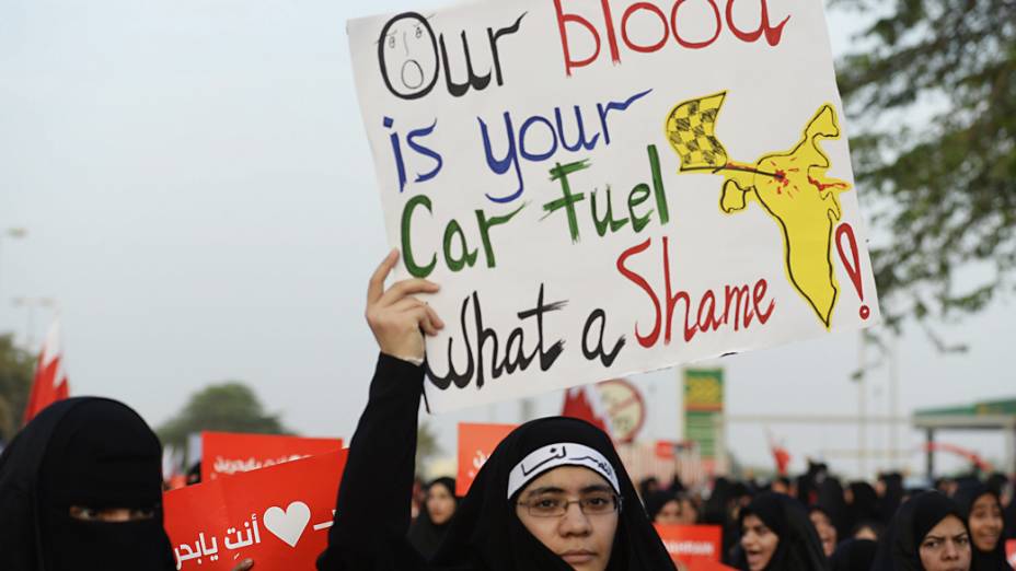 Mulher carrega cartaz com a frase: "Nosso sangue é sua gasolina" durante protesto contra a realização do GP de Fórmula 1 no Bahrein