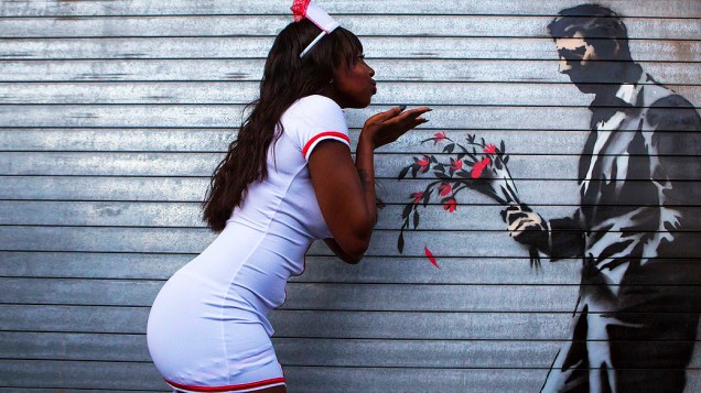 Dançarina posa em uma instalação do artista britânico Banksy na porta da frente do Clube Hustler em Nova York