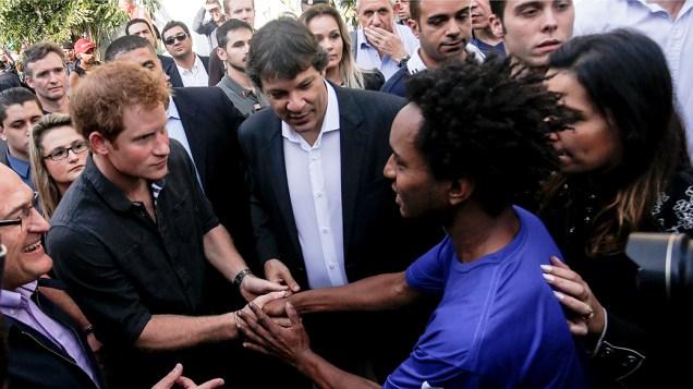 Príncipe Harry, acompanhado do prefeito de São Paulo, Fernando Haddad, cumprimenta as pessoas durante visita a Cracolândia, na região central da capital