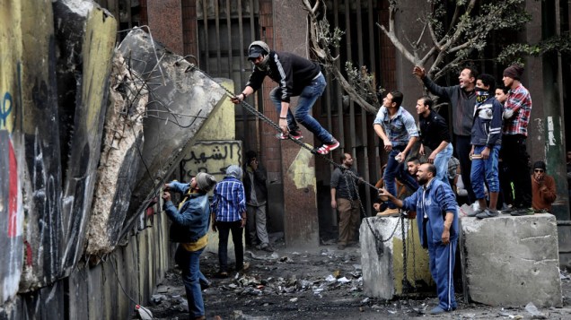Manifestantes egípcios tentam derrubar um muro construído para impedi-los de chegar ao Parlamento e ao prédio do Gabinete perto da Praça Tahrir no Cairo, Egito