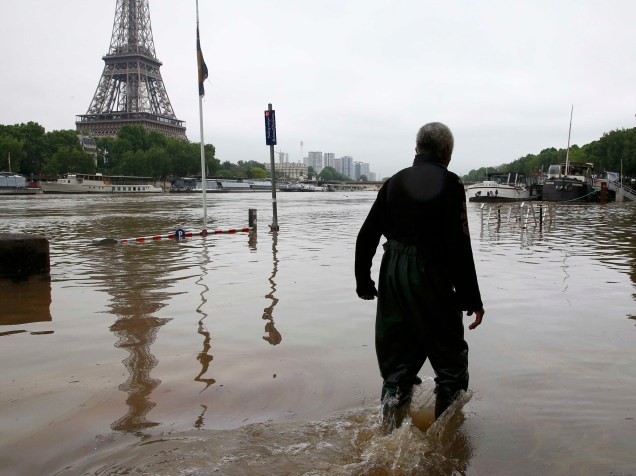Homem caminha em uma avenida inundada às margens do Rio Sena, em Paris