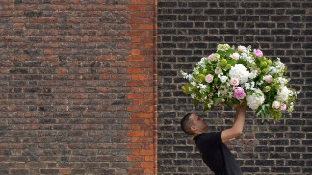 Homem carrega arranjos durante a Exposição de Flores de Chelsea, em Londres