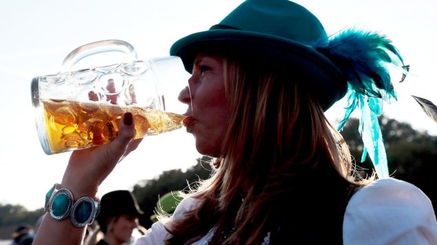 Mulher bebe cerveja fora de uma barraca durante o 180° Oktoberfest em Munique, na Alemanha