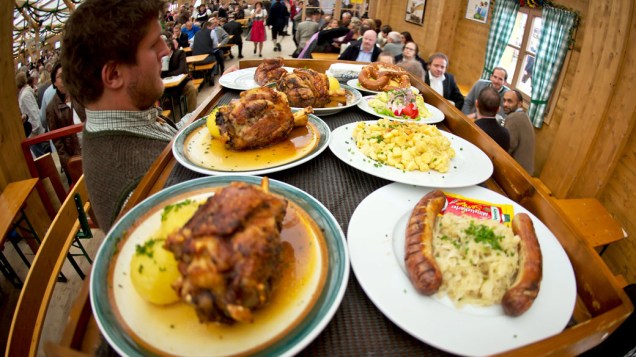 Um garçom traz uma bandeja grande de refeições no 180° Oktoberfest em Munique, na Alemanha