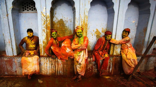 Devotos hindus cobertos de água colorida e pó sentam-se em um templo durante o Festival Holi, na aldeia de Nandgaon no norte do estado de Uttar Pradesh, Índia