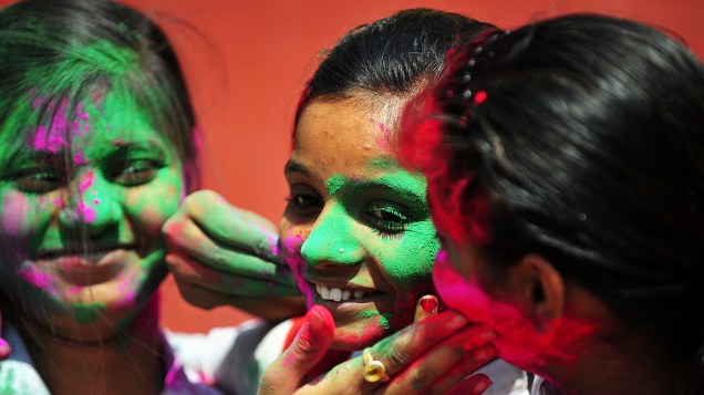 Estudantes brincam com pó colorido fora de uma escola em Allahabad, durante o Festival Holi, Índia