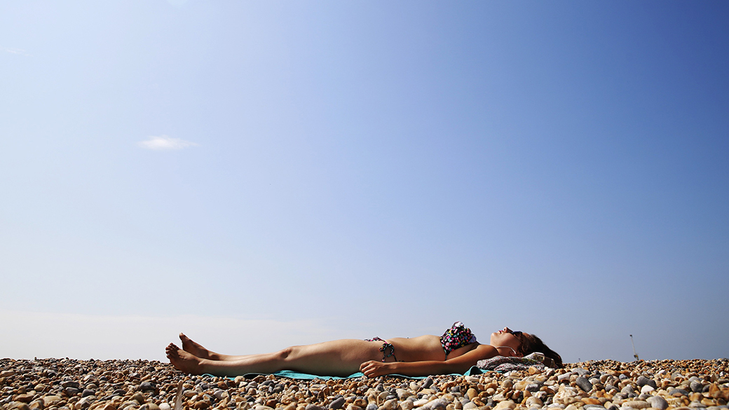 Estudante é fotografada tomando sol um dia quente de verão, na praia de Brighton, no sul da Inglaterra