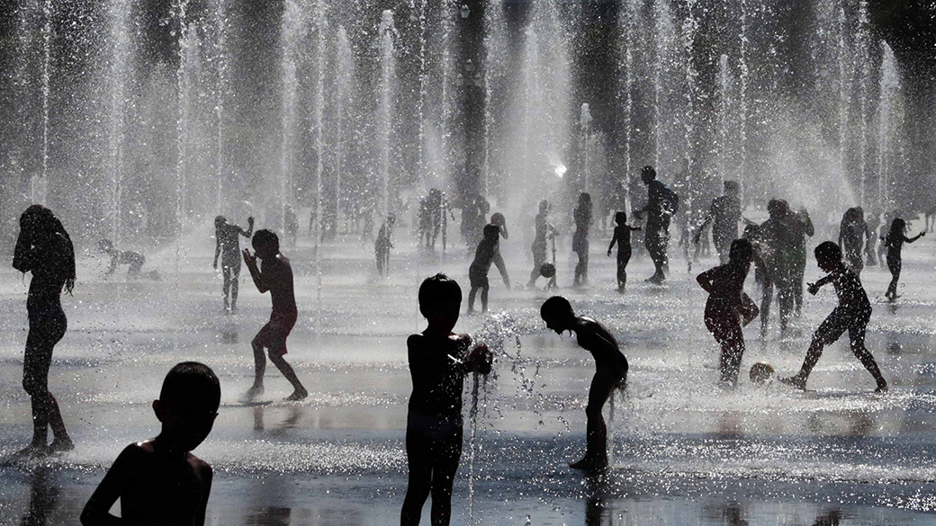 Crianças se refrescam em uma fonte, durante um dia de verão quente e ensolarado em Nice, sudeste da França