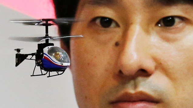 Membro da equipe de brinquedos japoneses e eletrodomésticos  CCP Co. opera um Nano-Falcon,  o menor helicóptero de controle remoto infravermelho do mundo, na Tokyo Toy Show, em Tóquio