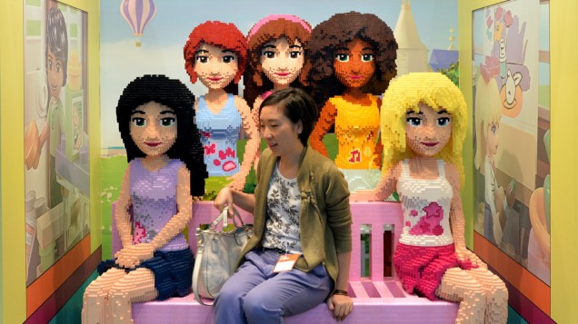 Visitante senta-se entre as figuras femininas em tamanho real feitos de blocos de Lego durante a Tokyo Toy Show