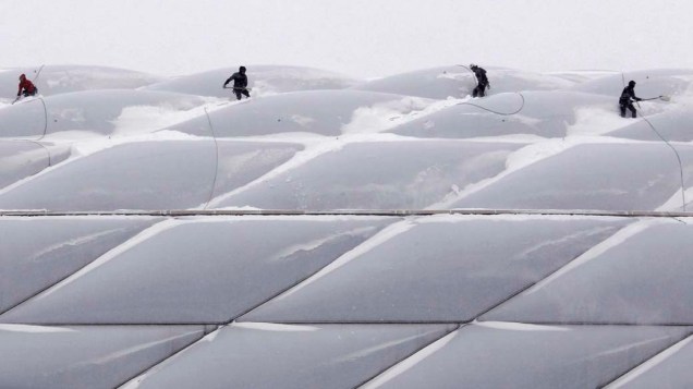 Trabalhadores removem neve do telhado de uma arena em Munique, Alemanha