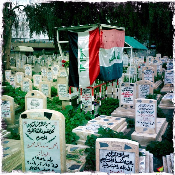 Bandeiras iraquianas sobre lápides no cemitério dos mártires sunitas em Bagdá