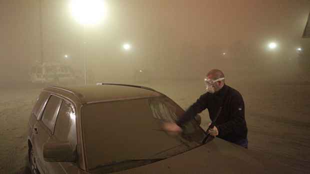 Um homem limpa as cinzas de seu carro em uma cidade próxima ao vulcão Grimsvotn, na Islândia