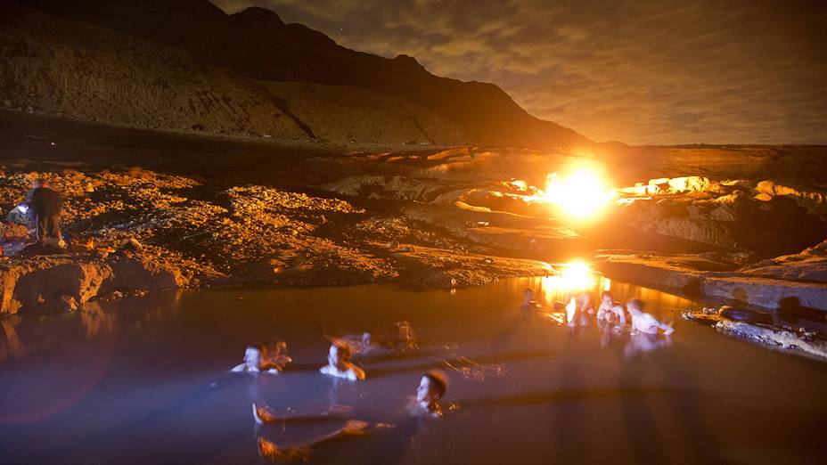 Israelenses aproveitam para se banhar em águas termais na costa do mar Morto, próximo ao Kibutz de Ein Gedi, enquanto observam o céu à espera da chuva de meteoro de Gêmeos, que estava prevista para ocorrer nesta sexta-feira (14)