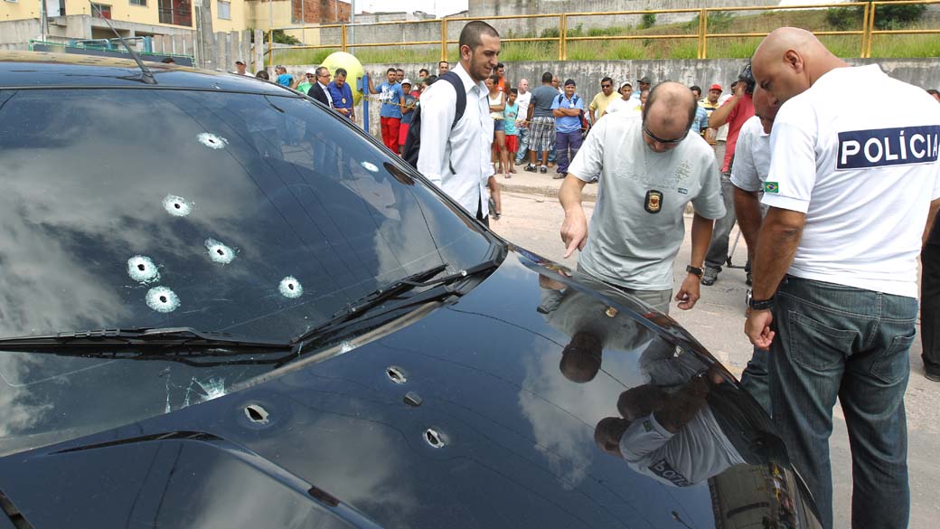 Policiais próximos do veículo do prefeito de Jandira, Braz Paschoalin, em frente a Rádio Astral FM, com as marcas dos disparos