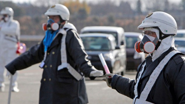 Oficiais japoneses usam proteção especial para evacuar moradores da cidade de Fukushima - 12/03/2011