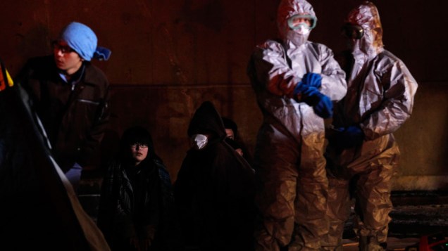 Oficiais próximos a famílias que evacuaram a área perto da usina nuclear de Fukushima, no Japão Oficiais próximos a famílias que evacuaram a área perto da usina nuclear de Fukushima, no Japão