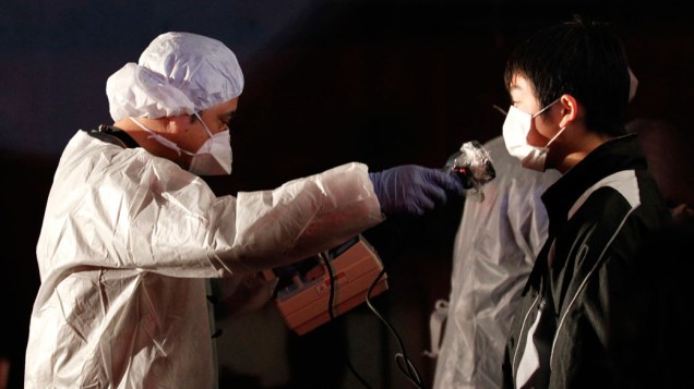 Oficial mede nível de radiação em jovem que evacuou a área perto da usina nuclear de Fukushima, no Japão