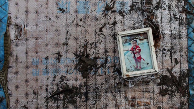 Foto de criança em escombros de casa na cidade de Kensennuma, Japão