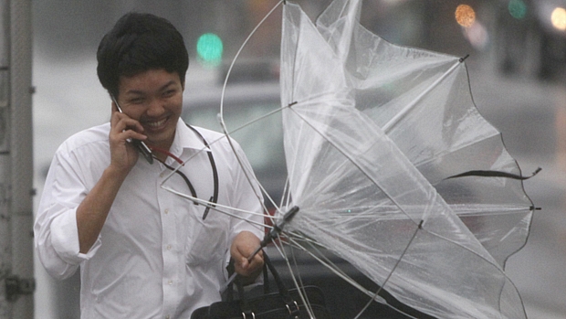 Homem se protege dos fortes ventos em Tóquio nesta quarta-feira: tufão deve chegar à capital ainda hoje.
