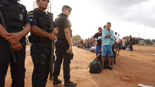 Fila de trabalhadores de Jirau aguarda por transporte, acompanhada por policiais de Rondônia: situação ainda é tensa