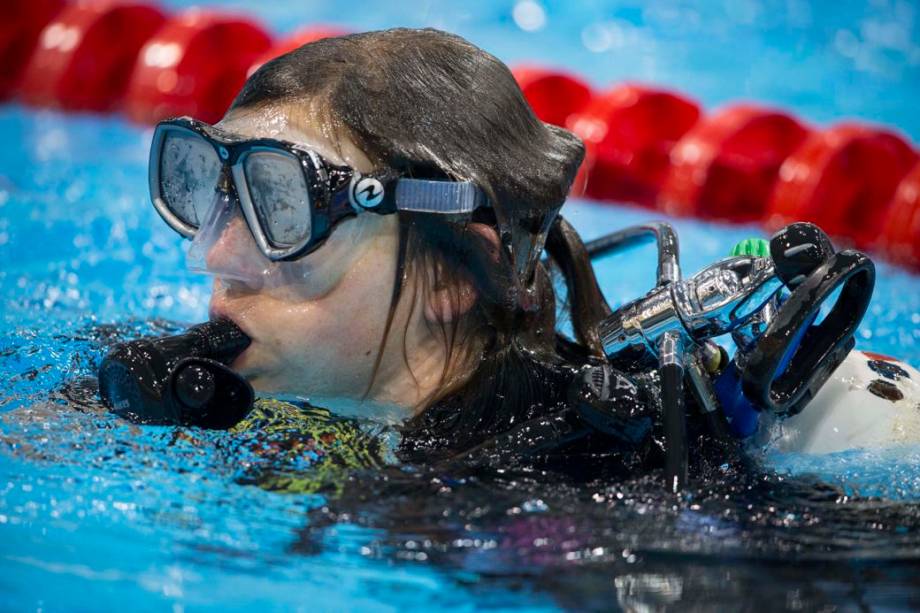 Mergulhadora que instala câmera sob a água na piscina olímpica