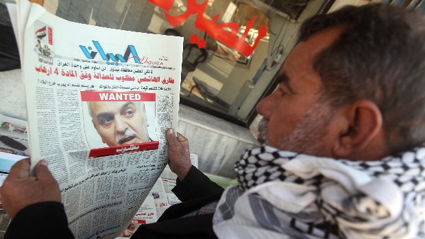 Homem lê jornal com foto do vice-presidente Tarek al Hashemi, procurado pela Justiça