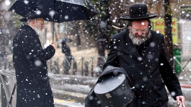 Judeus ultra-ortodoxos caminham sob a neve em Jerusalém, Israel