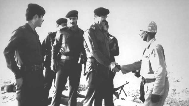 O presidente iraquiano Saddam Hussein (centro) cumprimenta soldado durante visita de inspeção das tropas  no Kuwait