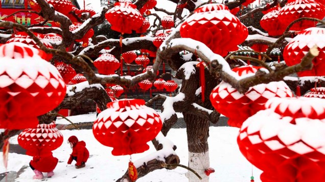 Criança brinca entre lanternas cobertas de neve em Pequim.