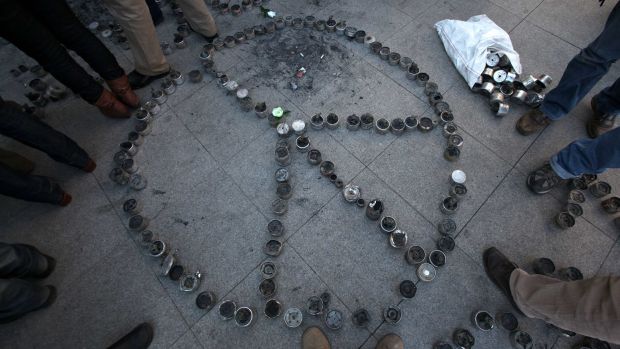 Estudantes chilenos fazem símbolo da paz com latas de gás lacrimogênio usadas pela polícia em frente ao palácio presidencial