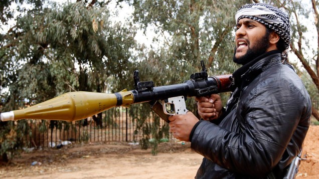 Rebelde líbio carrega RPG (lança granadas-foguete) durante o conflito em Bengasi, na Líbia