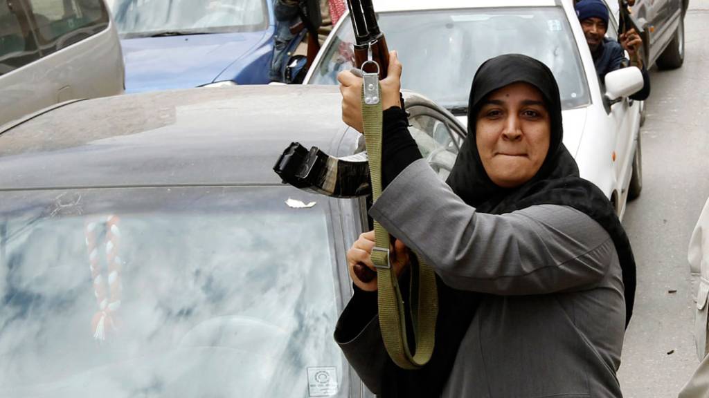 Mulher carrega metralhadora Ak-47 durante os protestos contra o ditador Muamar Kadafi em Benghazi, na Líbia
